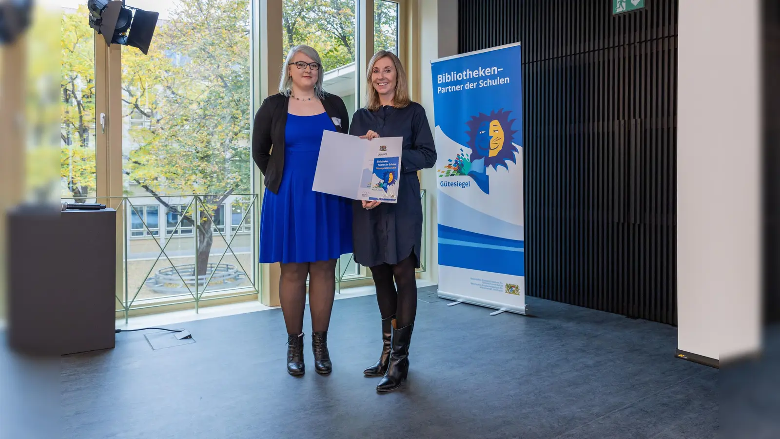Kultusministerin Anna Stolz (r.) überreicht das Gütesiegel an Bibliotheksmitarbeiterin Jana Hupfer. Zusammen mit Sabina Graßl verhilft sie Schülern bei der Erlangung des „Medienführerscheins” zu mehr Kompetenz im Umgang mit dem Internet. (Foto: Johannes Kiefer)