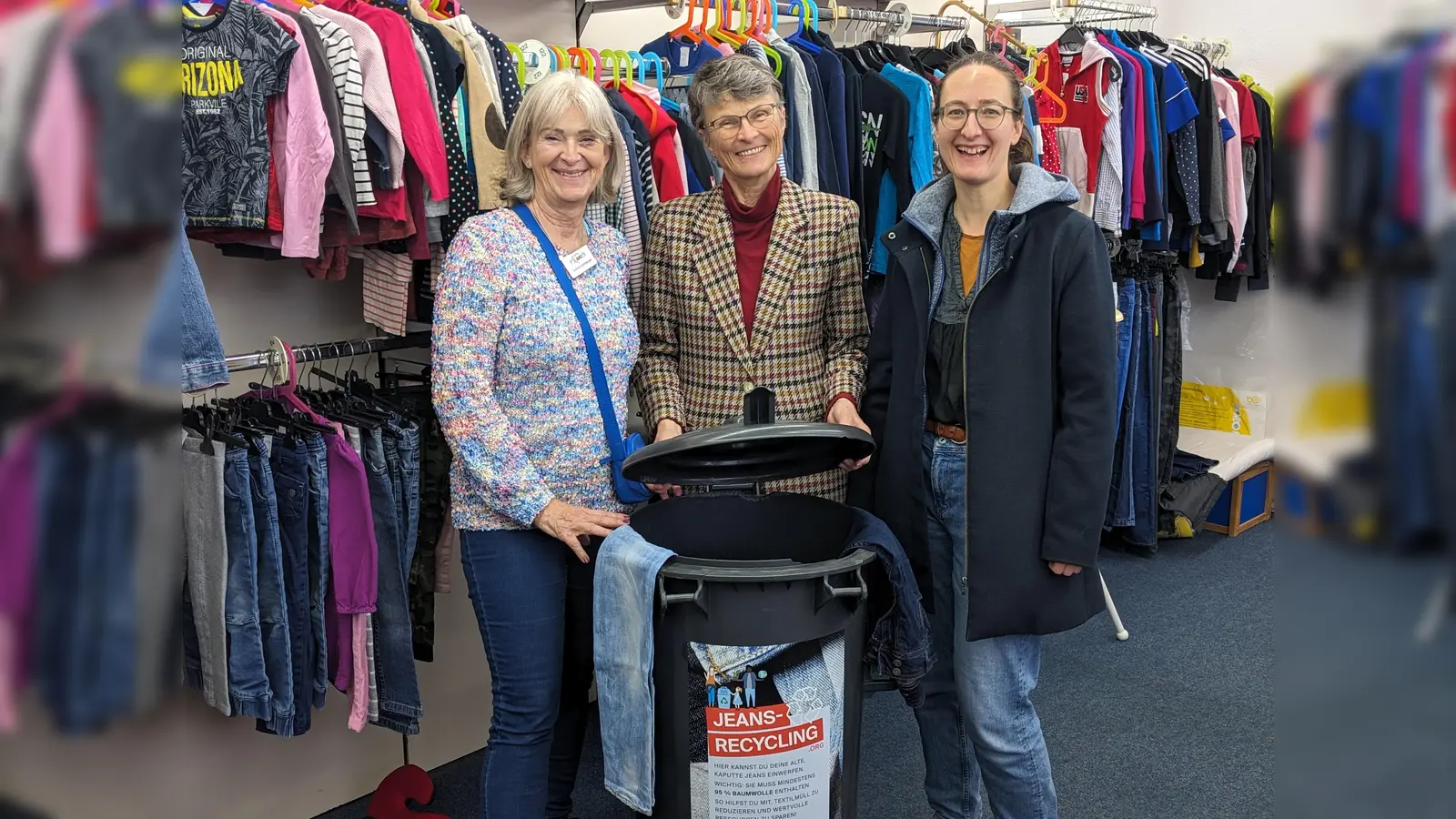 (V. l. n. r.:) Sylvia Lemberger (Klawotte USH), Ursula Baumann und Lena Gierl (AG Müllvermeidung – Klimaneutral 2035 USH) präsentieren hier die neue Jeans-Sammeltonne in der Klawotte Unterschleißheim.  (Foto: AG Müllvermeidung – Klimaneutral 2035 OSH und USH)