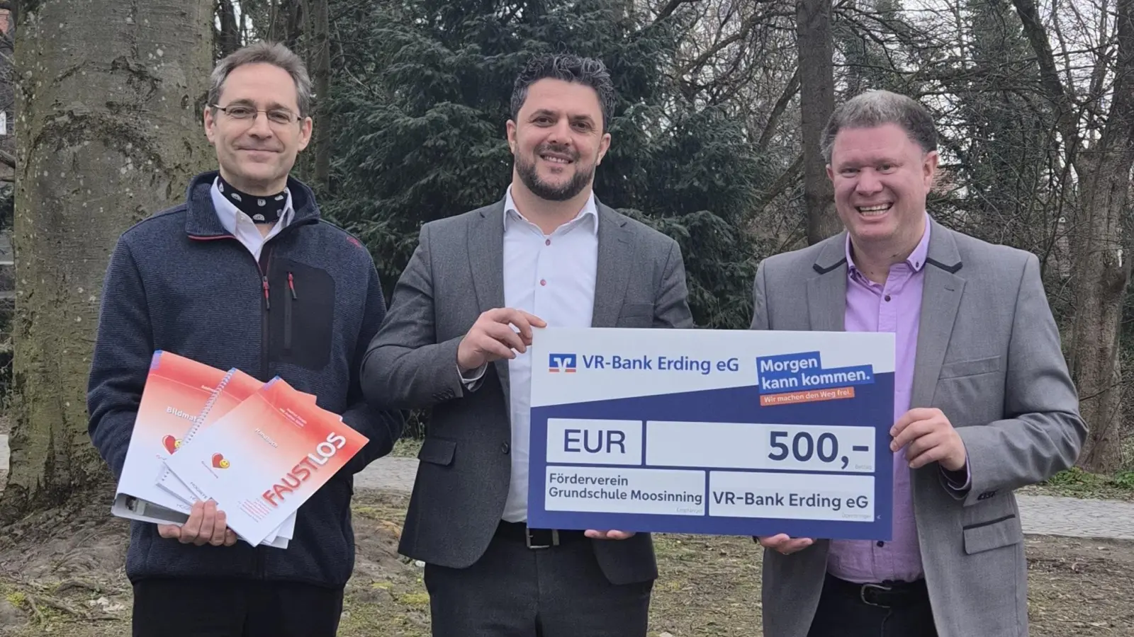 Thomas Gobmaier (Vorsitzender des Fördervereins GS Moosinning), Hamdi Salishta (VR Bank Erding eG) und Thomas Speyerer (stellv. Vorsitzender des Fördervereins GS Moosinning) präsentieren den Spendenscheck und einen Teil des beschafften „Faustlos“-Materials (von links). (Foto: VRB)