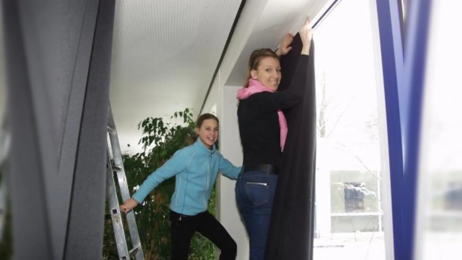 Laura (l.) und Kübra arbeiten hier daran, mittels Stoffbahnen die großen Fenster für die Aufführungen zu verdunkeln. (Foto: Eva Schraft)