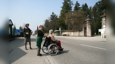 Ein sicherer Überweg über die befahrene Bergsonstraße kann noch dauern. Zwar hat das KVR den Zebrastreifen für „gleich nach den Osterferien“ versprochen, doch muss nun erst einmal ein gemeinsamer Ortstermin von VR, Baureferat und Straßenbeleuchtung gefunden werden. Auf die hilfsbereiten Helfer der Gärtnerei müssen die Querungswilligen also noch eine Weile zurückgreifen. V.l. Franziska Miroschnikoff, Gärtnerei-Mitarbeiterin Rita Straßl mit Kundin. (Foto: US)