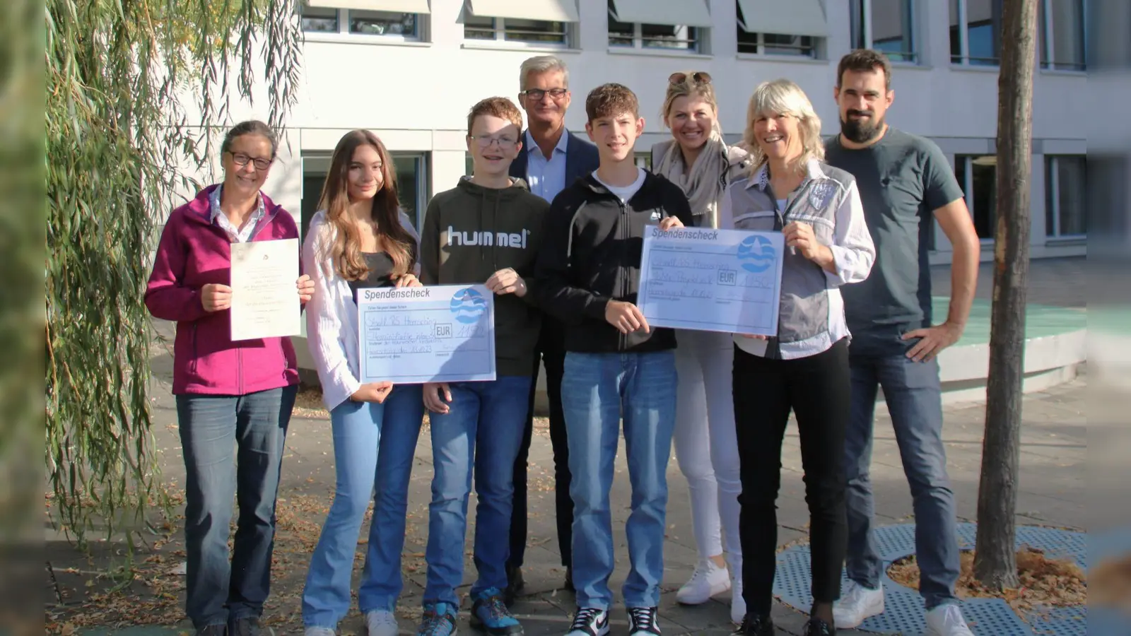 Die Schülerinnen und Schüler überreichten Margarete Bader von der Elterninitiative (links) und Sabine Behringer von JoMa-Projekt e.V. (2. von rechts) Spendensummen in Höhe von jeweils 1.150 Euro. Bei der Übergabe waren (hintere Reihe von links) Schulleiter Christian Schmitz sowie die Lehrkräfte Melanie Wederhake und Andreas Drexl anwesend. (Foto: Realschule Herrsching)