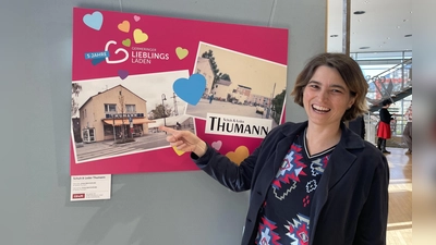 Verena Thumann zeigt auf die alten Fotos aus dem Familienalbum, die das alte Geschäftshaus in der Unteren Bahnhofstraße zeigen. (Foto: pst)