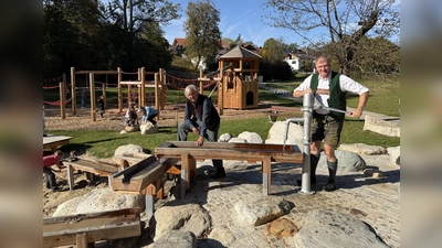 Bürgermeister Stefan Schelle (r.) testet mit Spielplatzplaner Peter Hohenauer vor der Eröffnung den Wasserspielbereich mit Pumpe.  (Foto: Gemeinde Oberhaching)