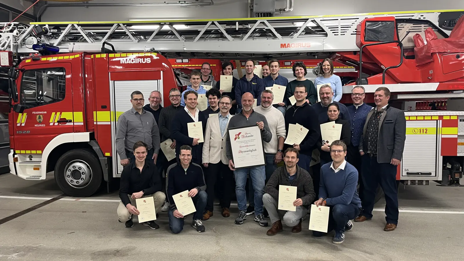 Die Freiwillige Feuerwehr u.a. mit 1. Kommandant Felix Lechner (rechts), 2. Kommandant Philipp Hergert (links stehend), Vorsitzendem Andreas Böll (Mitte, weißes Sakko), Ehrenmitglied Konrad Grabmaier (Mitte, große Urkunde) und stv. Vorsitzendem Ernst Marschke (Mitte, heller Pulli). (Foto: FFW)