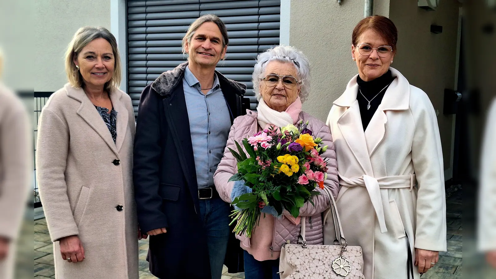 100. Fernwärmeanschluss: Sabine Abtmeier und Jan Haas (Gemeindewerke Gilching) gratulieren Magdalena und Katrin Laternser mit einem Blumenstrauß (v.l.). (Foto: Gemeindewerke Gilching)